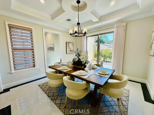 dining area featuring an inviting chandelier, coffered ceiling, and ornamental molding