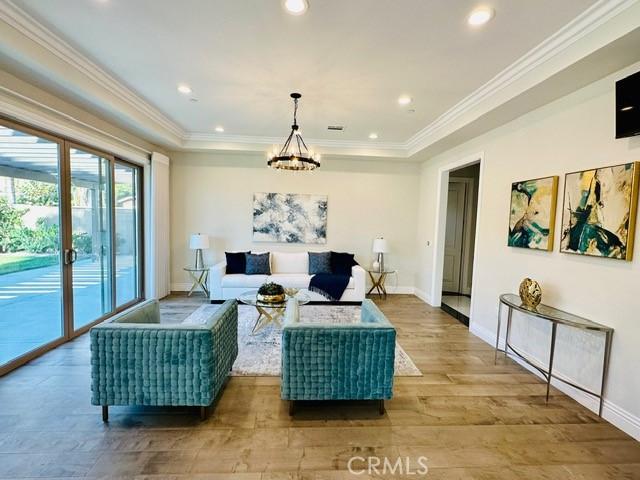 living room with hardwood / wood-style flooring, a notable chandelier, and crown molding