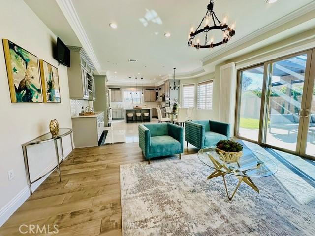 living room with a chandelier, light wood-type flooring, and crown molding