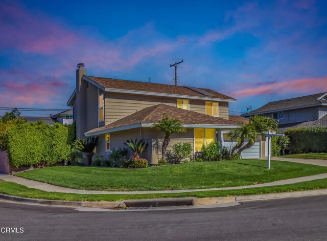 traditional home with a garage, a chimney, concrete driveway, and a front yard