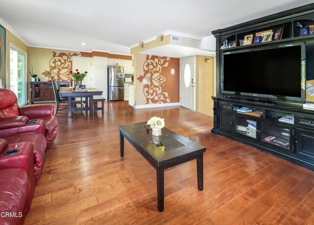 living area featuring visible vents, ornamental molding, and wood finished floors