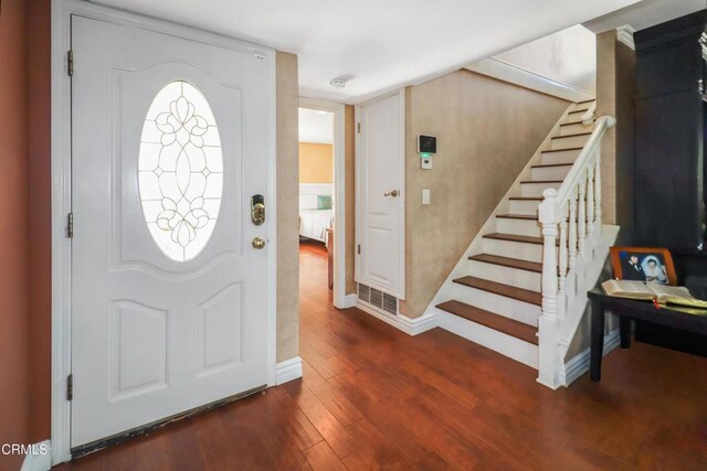 entrance foyer with baseboards, visible vents, wood finished floors, and stairway