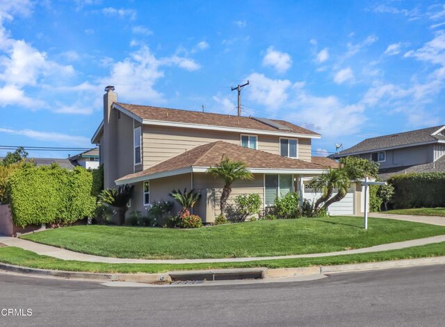 traditional-style home with a chimney, a front yard, and concrete driveway