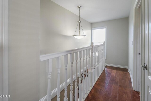 corridor featuring baseboards, an upstairs landing, and hardwood / wood-style floors