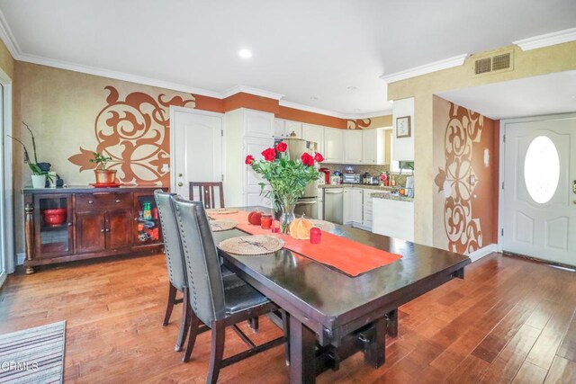 dining space with crown molding, visible vents, and light wood-type flooring