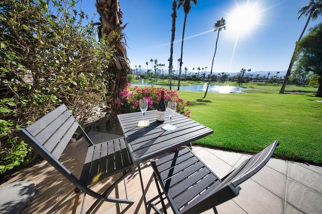 view of community with a lawn, a water view, and a patio