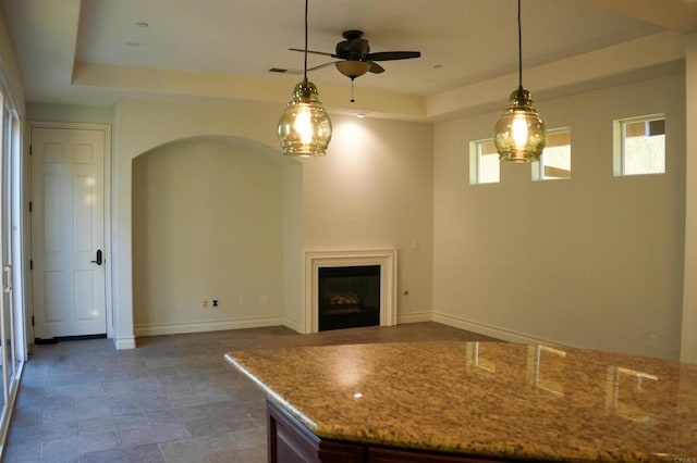 kitchen featuring a tray ceiling, ceiling fan, and hanging light fixtures