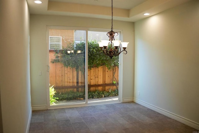 interior space with a tray ceiling and an inviting chandelier