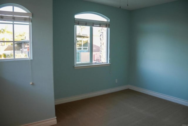 spare room featuring dark colored carpet