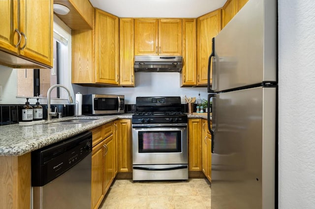 kitchen with light stone countertops, appliances with stainless steel finishes, and sink