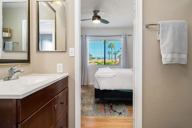 bathroom featuring ceiling fan, wood-type flooring, a textured ceiling, and vanity