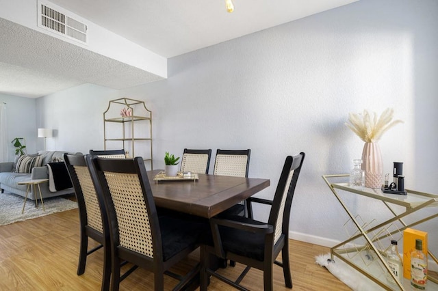 dining room with a textured ceiling and light hardwood / wood-style flooring