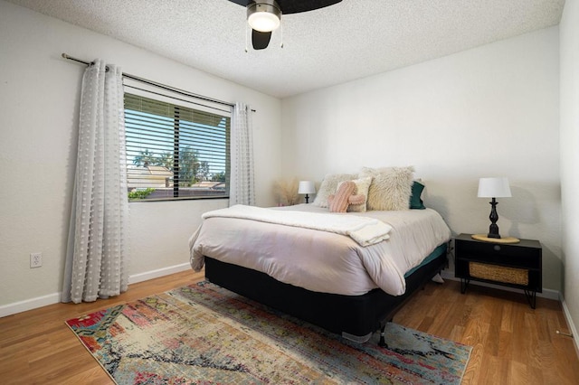 bedroom with hardwood / wood-style floors, a textured ceiling, and ceiling fan