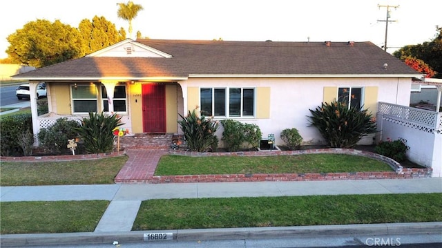 single story home with covered porch and a front lawn