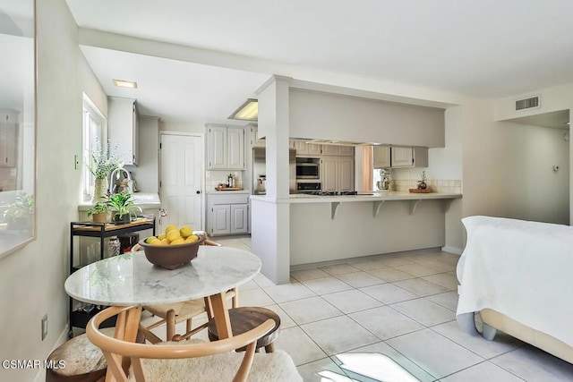 kitchen featuring kitchen peninsula, light tile patterned floors, stainless steel double oven, and gray cabinets