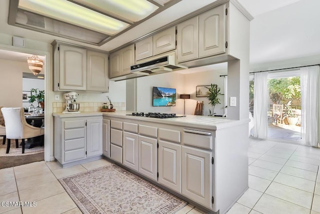 kitchen featuring kitchen peninsula, black gas stovetop, light tile patterned floors, and range hood