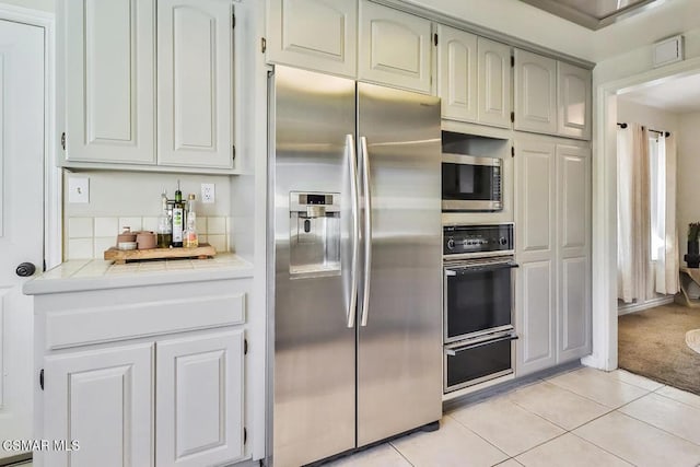 kitchen featuring tile counters, light tile patterned flooring, and stainless steel appliances