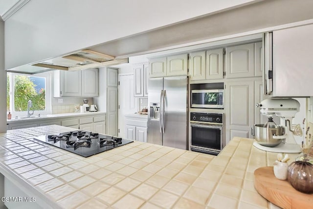 kitchen featuring sink, tile counters, and black appliances