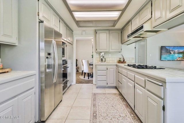 kitchen featuring black oven, stainless steel fridge, gas stovetop, and light tile patterned floors