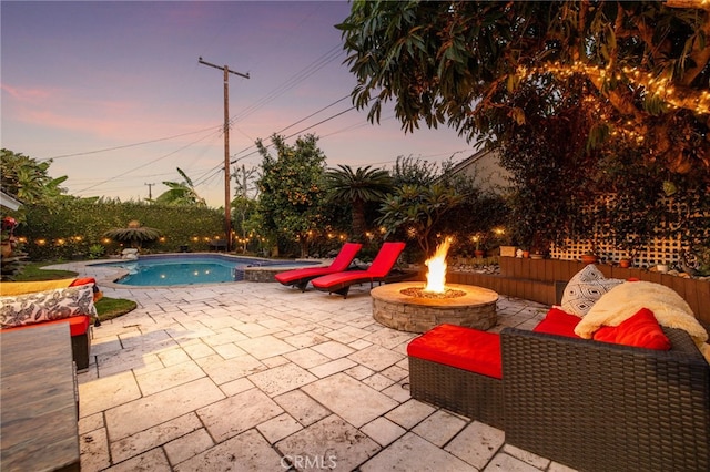 patio terrace at dusk featuring a fenced in pool and an outdoor fire pit