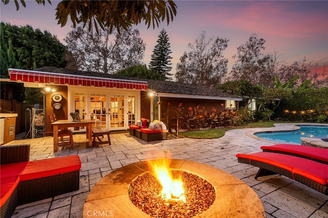 pool at dusk featuring a patio and a fire pit