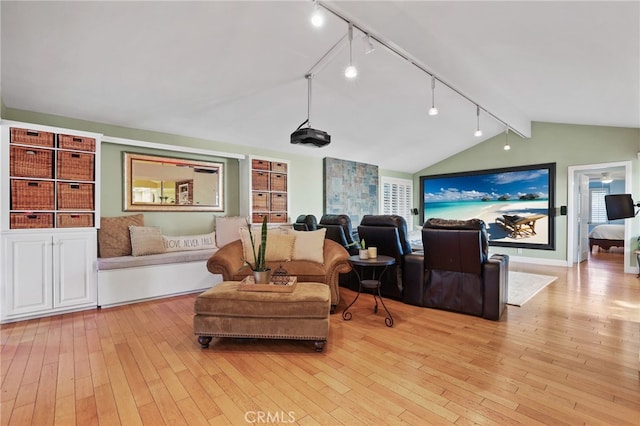 living room featuring lofted ceiling, rail lighting, and light hardwood / wood-style flooring