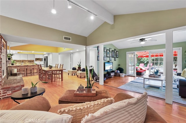 living room featuring light wood-type flooring, ceiling fan, and vaulted ceiling with beams