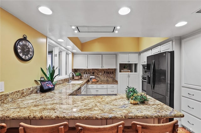 kitchen featuring black refrigerator with ice dispenser, white cabinetry, tasteful backsplash, kitchen peninsula, and a breakfast bar