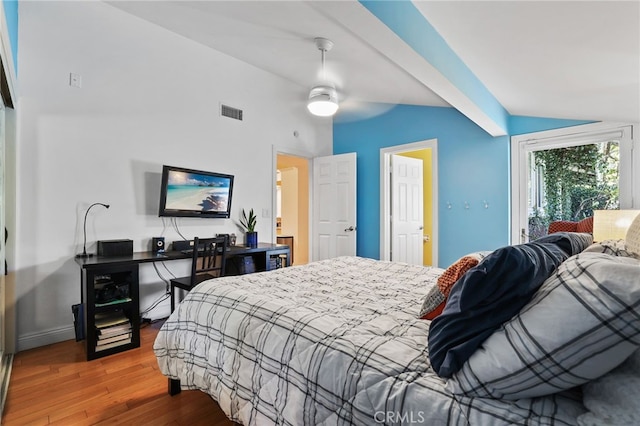 bedroom with ceiling fan, vaulted ceiling with beams, and hardwood / wood-style flooring