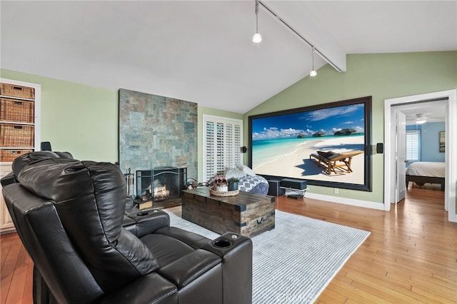 living room with lofted ceiling with beams, a fireplace, and light hardwood / wood-style floors