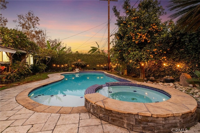 pool at dusk featuring an in ground hot tub