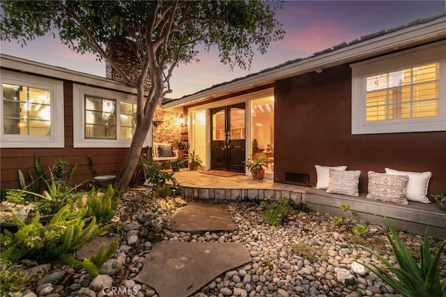 back house at dusk with french doors and a patio