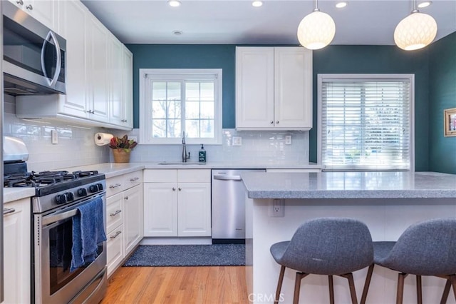 kitchen with white cabinets, decorative light fixtures, sink, and appliances with stainless steel finishes