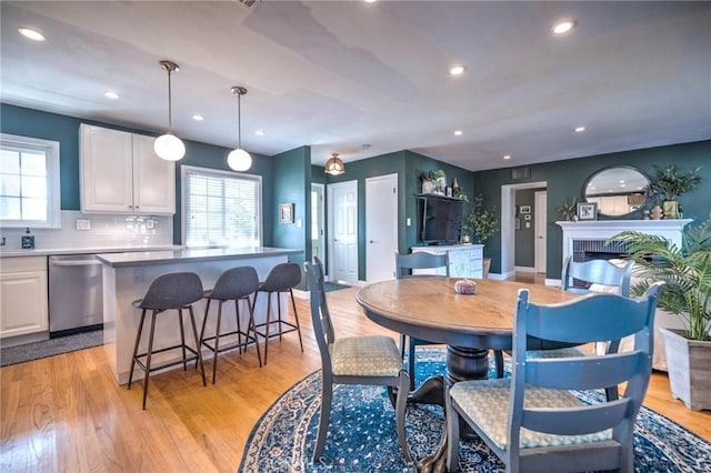 dining space featuring light hardwood / wood-style floors and a brick fireplace