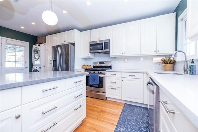 kitchen with white cabinetry, stacked washing maching and dryer, and appliances with stainless steel finishes