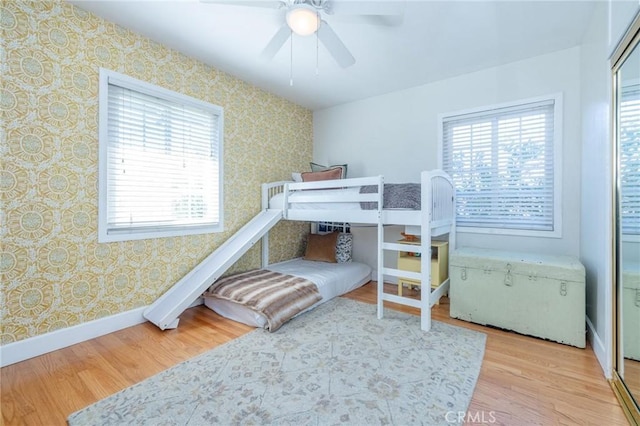 bedroom featuring ceiling fan, wood-type flooring, and multiple windows