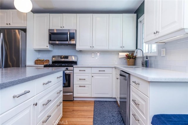 kitchen featuring sink, white cabinets, stainless steel appliances, and light wood-type flooring