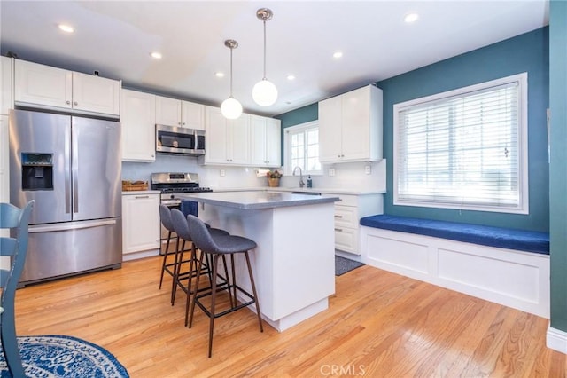 kitchen with white cabinets, pendant lighting, light hardwood / wood-style floors, and appliances with stainless steel finishes