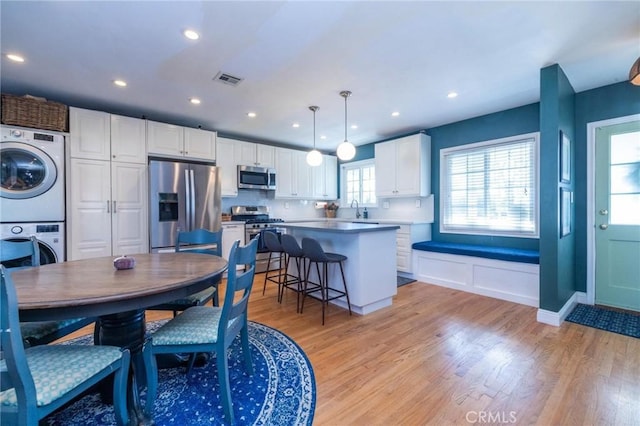 dining room with light hardwood / wood-style flooring, stacked washer / dryer, and sink