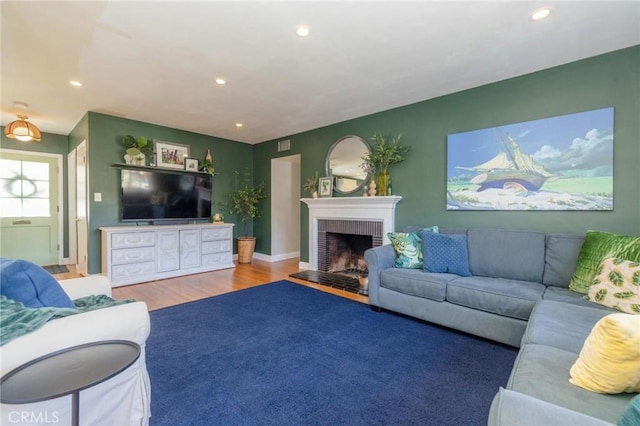 living room with wood-type flooring and a brick fireplace