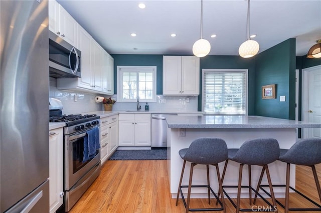 kitchen featuring white cabinetry, sink, stainless steel appliances, and light wood-type flooring