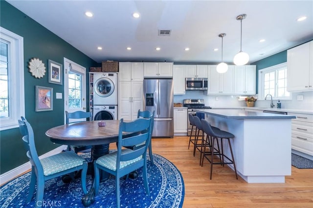 dining room featuring sink, light hardwood / wood-style floors, and stacked washer / drying machine