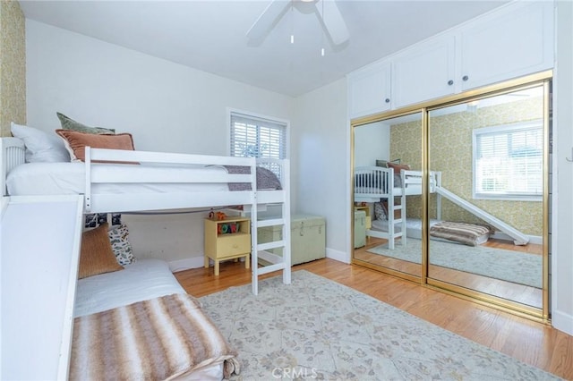 bedroom with multiple windows, ceiling fan, a closet, and light hardwood / wood-style floors