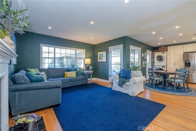 living room with hardwood / wood-style flooring, a healthy amount of sunlight, and stacked washer and clothes dryer