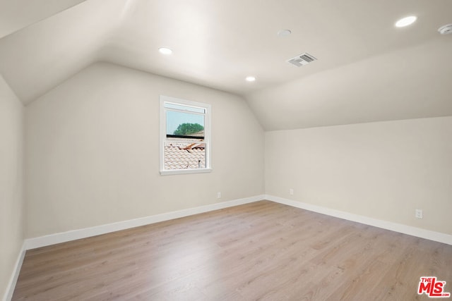 bonus room with light wood-type flooring and vaulted ceiling