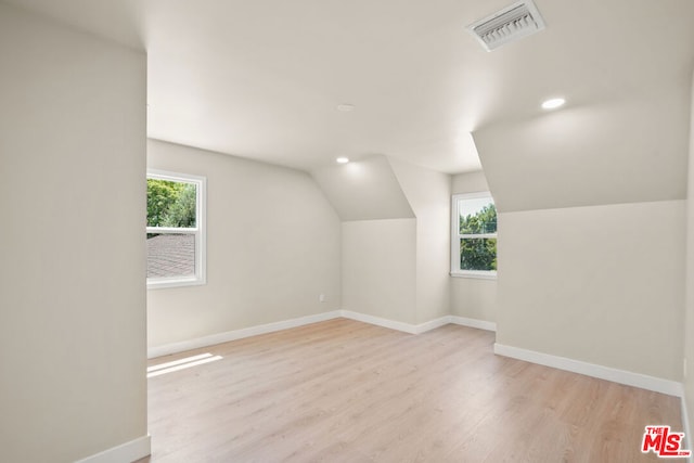 bonus room with lofted ceiling and light wood-type flooring