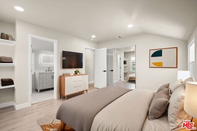 bedroom with connected bathroom, light hardwood / wood-style flooring, lofted ceiling, and sink