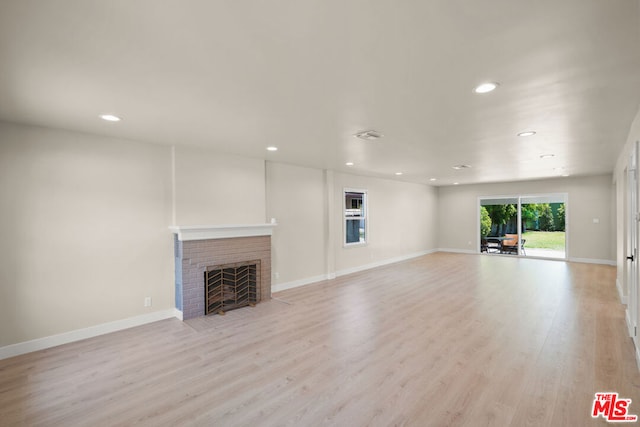 unfurnished living room featuring light hardwood / wood-style floors and a brick fireplace