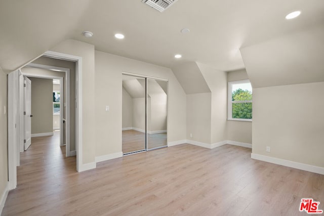 additional living space with light hardwood / wood-style flooring and lofted ceiling