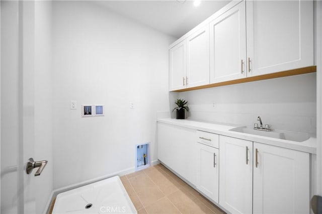 laundry room featuring cabinets, light tile patterned floors, sink, and hookup for a washing machine